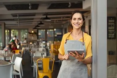 Woman running a cafe using a tablet device
