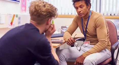 Mental health professional or teacher talking to teenage boy