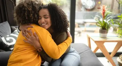 Mother and teenager hugging and smiling sitting on the sofa