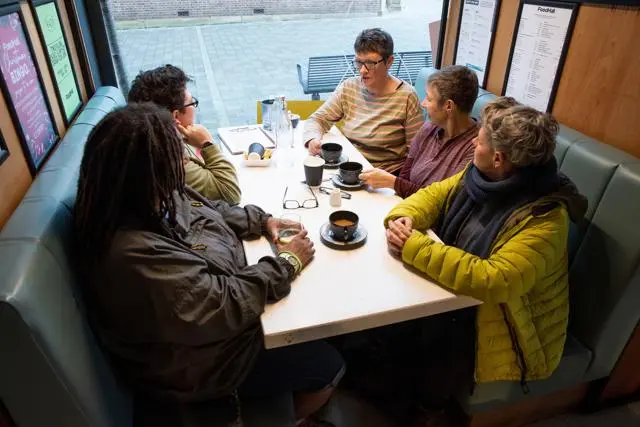 Five women over 50 chat with coffee in a coffee shop
