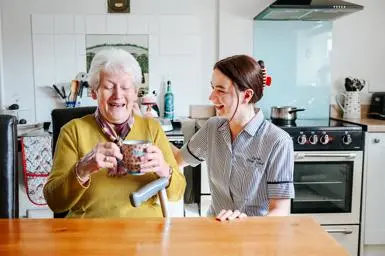 Care worker chatting with an older woman in a kitchen