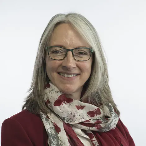 Caroline Topping, councillor, wearing glasses, red jacket, a butterfly patterned scarf, hair is cut past the shoulders.