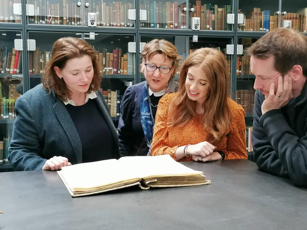 A group of people looking at a book of historical records