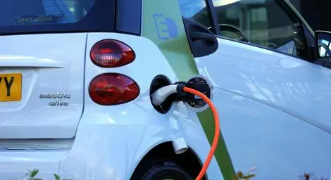 A white car charging with an orange cable.