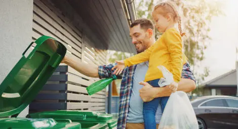 Man and daughter using the green recycle bin