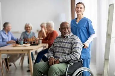 Female care worker or nurse standing behind elderly man in wheelchair