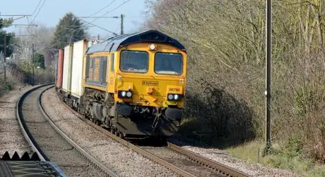 A freight train drives along the tracks pulling shipping containers