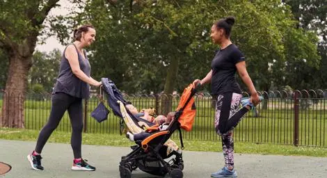 Two mums with prams stretching in a park getting ready to run