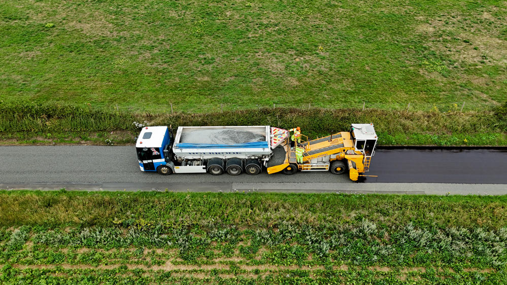 An image of highways vehicles applying surface dressing to a road