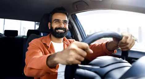 A man smiling whilst driving a car.