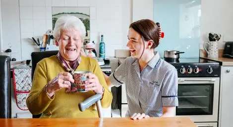 Care worker chatting with an older woman in a kitchen