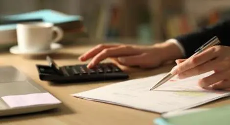 Woman using calculator and taking notes