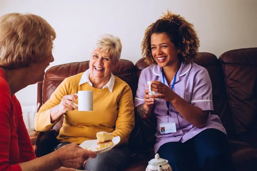 Women and healthcare worker enjoying tea and cake
