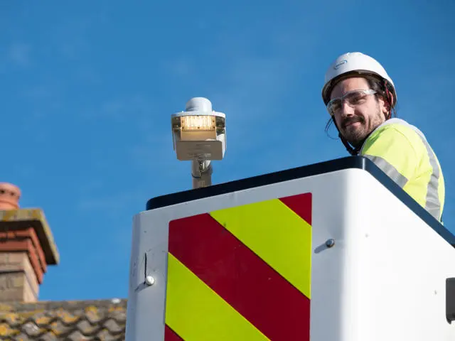 A man on a crane wearing a high vis jacket