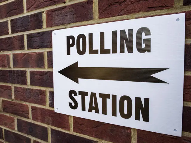 Polling station sign on brick wall