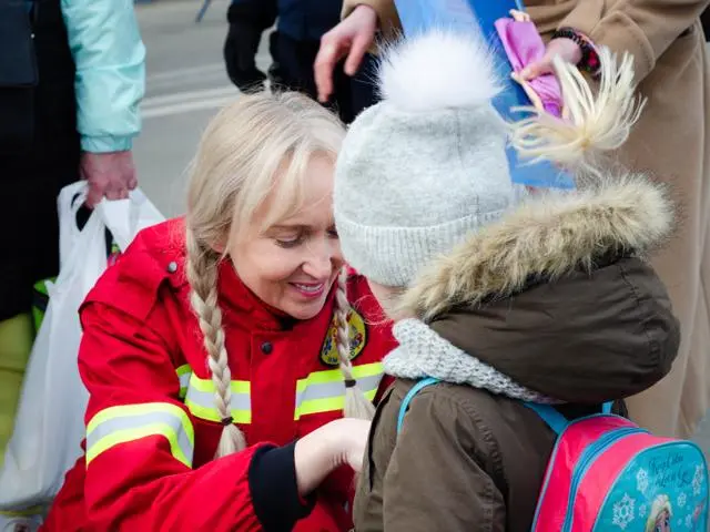 Woman in red jacket helping a young girl