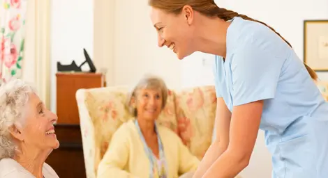 A social worker is smiling and helping two old ladies.