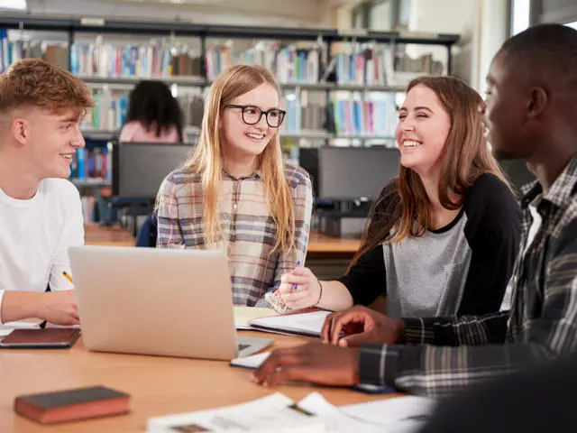 Four young people sitting around a laptop discussing the plans for Suffolk. Two females, two males .