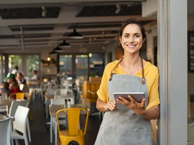 A woman standing in front of the restaurant business that she owns